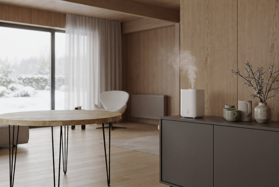 Ronde eiken eettafel in een woonkamer in de winter, met een luchtbevochtiger op het dressoir