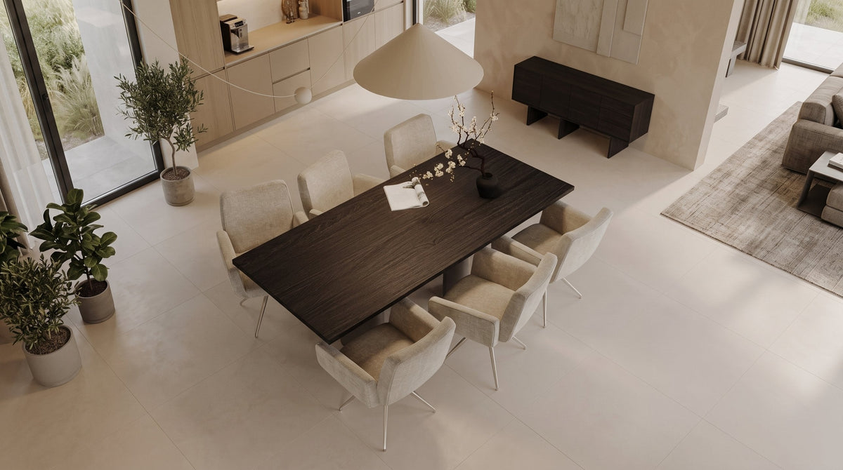 Donkere eiken eettafel met zes gestoffeerde stoelen in een lichte open woonruimte