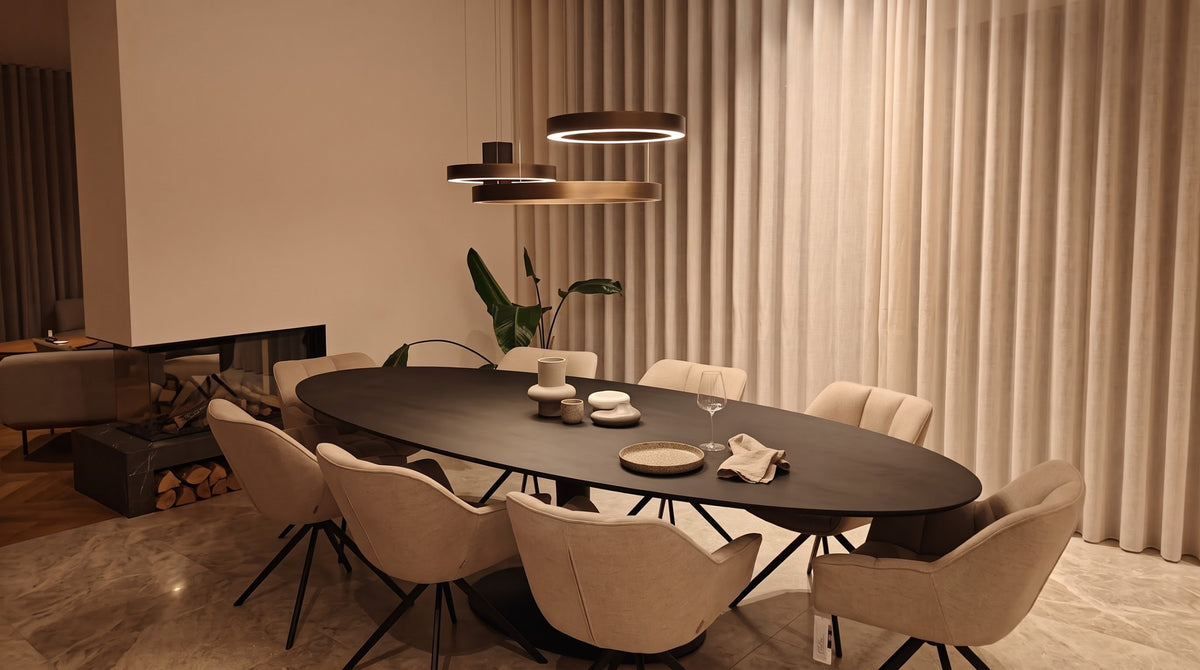 Zwarte ovale eettafel met beige draaistoelen en designverlichting